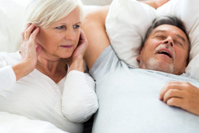 Senior man snoring and woman covering ears sleep apnea treatment 